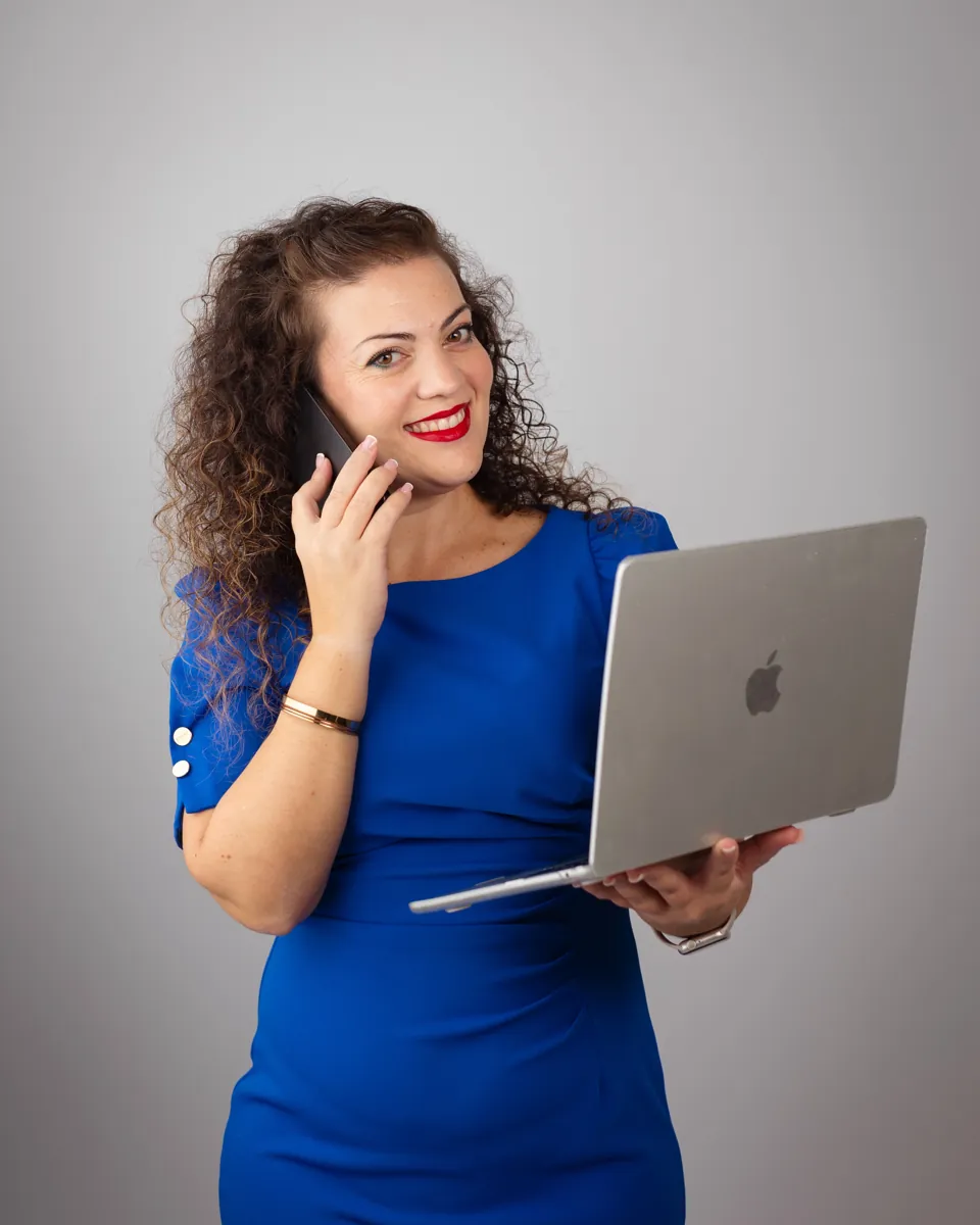 Irene Hernández hablando por teléfono con el portátil en la mano, sonriendo